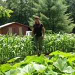 Bren standing in the raised bed gardens.